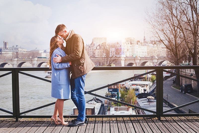 cita romántica, joven pareja besándose en el puente de París