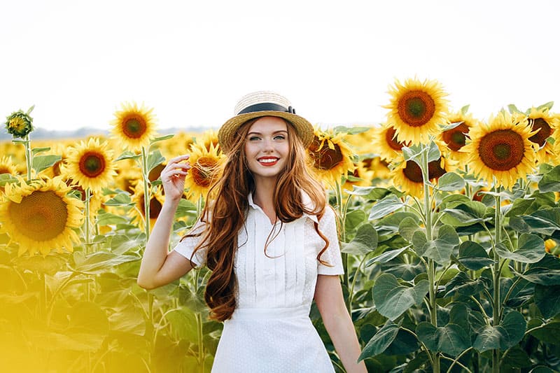 beautiful sweet sexy girl in a white dress walking on a field of sunflowers , smiling a beautiful smile,cheerful girl,style, lifestyle , ideal for advertising and photo sun shines bright and juicy