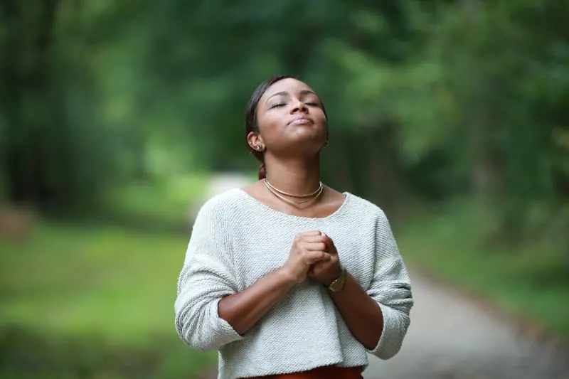 black woman praying in nature