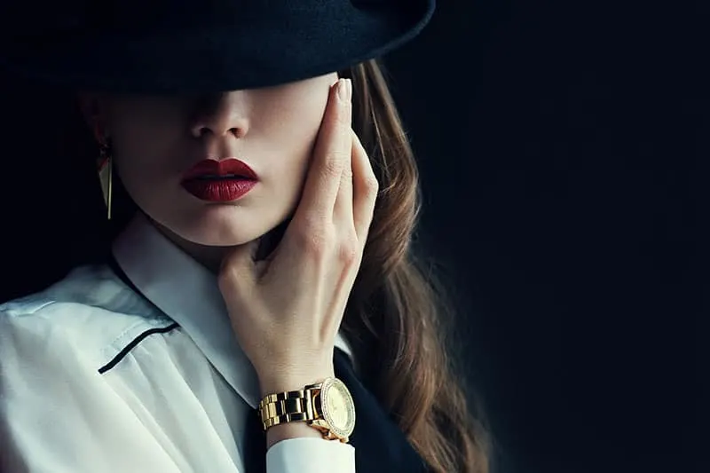 Indoor portrait of a young beautiful fashionable woman wearing stylish accessories. Hidden eyes with hat. Female fashion, beauty and advertisement concept. Close up. Copy space for text 