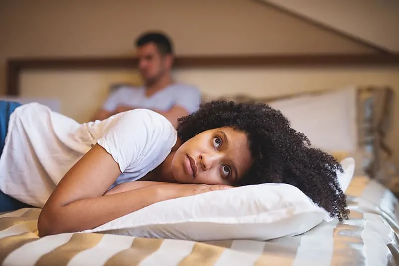 Sad woman lying on bed after an argument with her boyfriend.