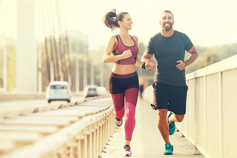Early morning workout. Happy couple running across the bridge. Living healthy lifestyle.