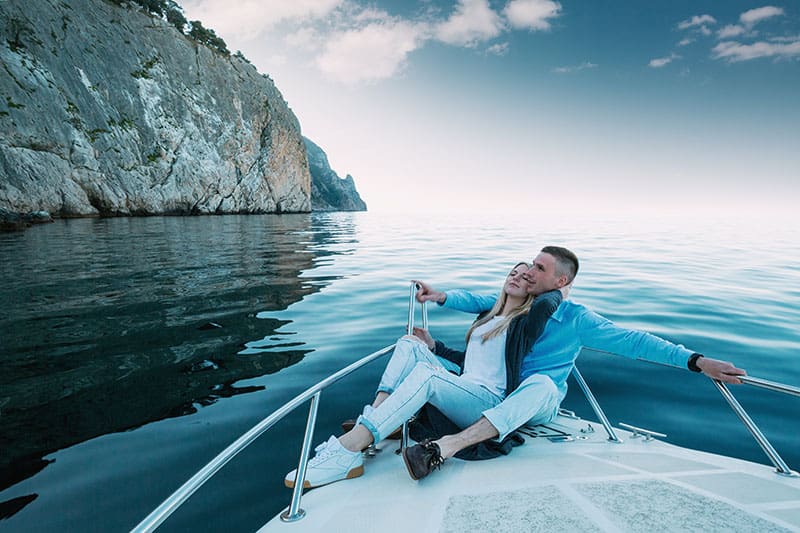 Giovane coppia che si rilassa su uno yacht. Un uomo ricco e felice e una donna in barca privata fanno una gita in mare