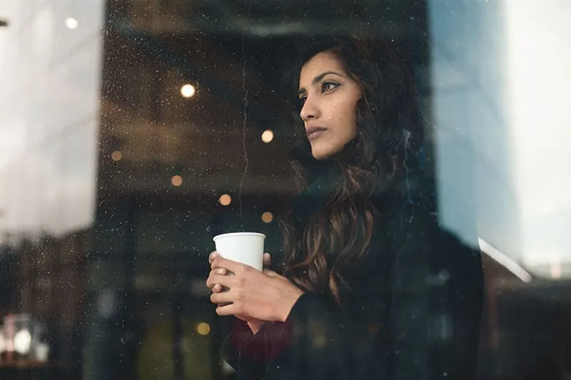 Young woman looking through rainy window