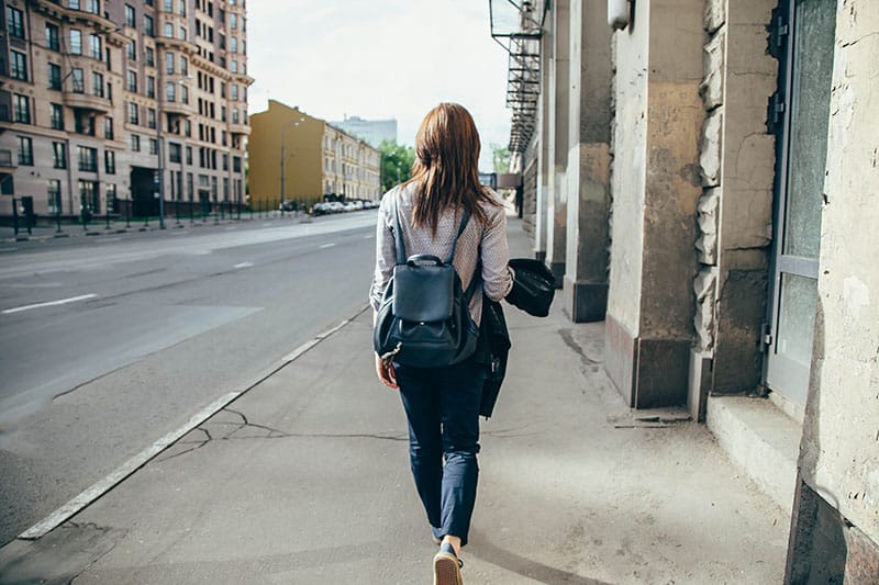 Back view of a hipster girl walking on city street