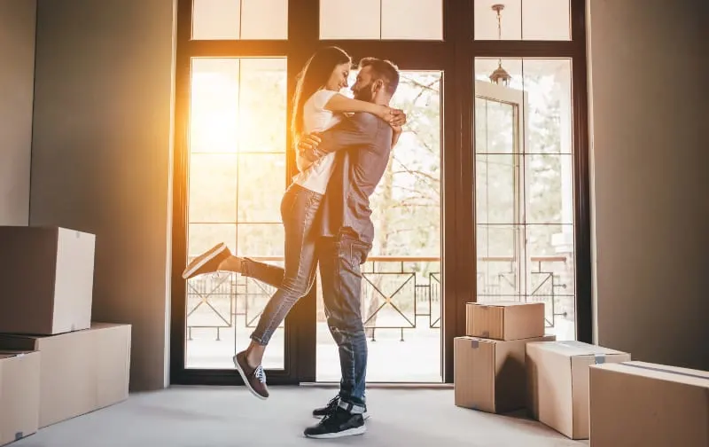 Happy couple with cardboard boxes in new house