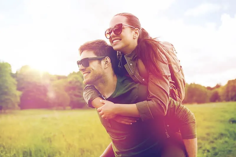 travel, hiking, backpacking, tourism and people concept - happy couple in sunglasses with backpacks having fun