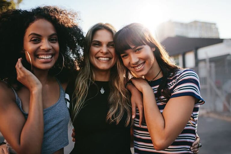Outdoor shot of three young women having fun on city street. Multiracial female friends enjoying a day around the city.