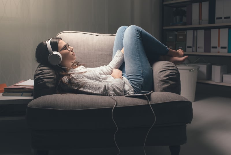 mujer escuchando musica y sentada en un sofa