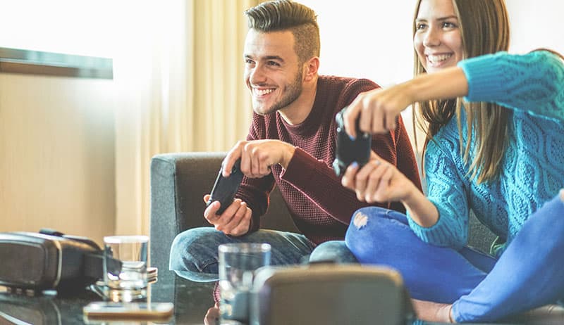 Amigos felices jugando a videojuegos - Los jóvenes se divierten con la nueva consola tecnológica en línea