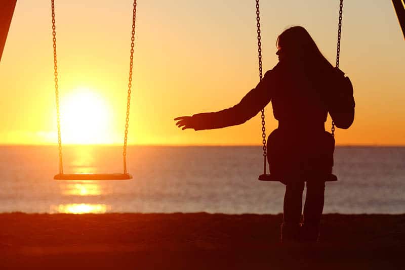 silhouette di donna sola seduta sull'altalena