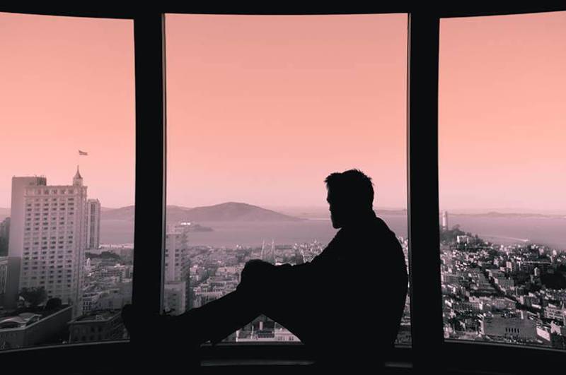 silhouette di uomo che guarda la città dalla finestra