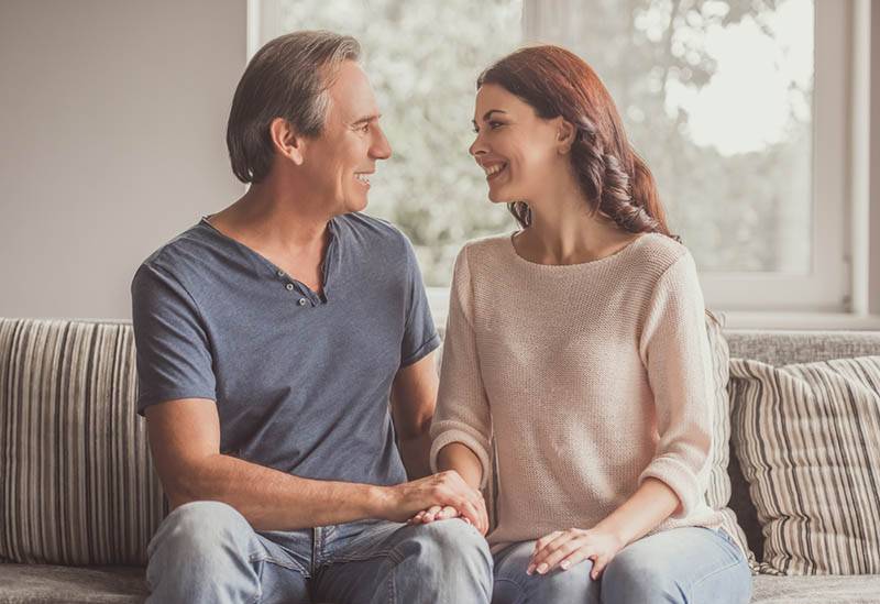 pareja sonriente sentada en casa