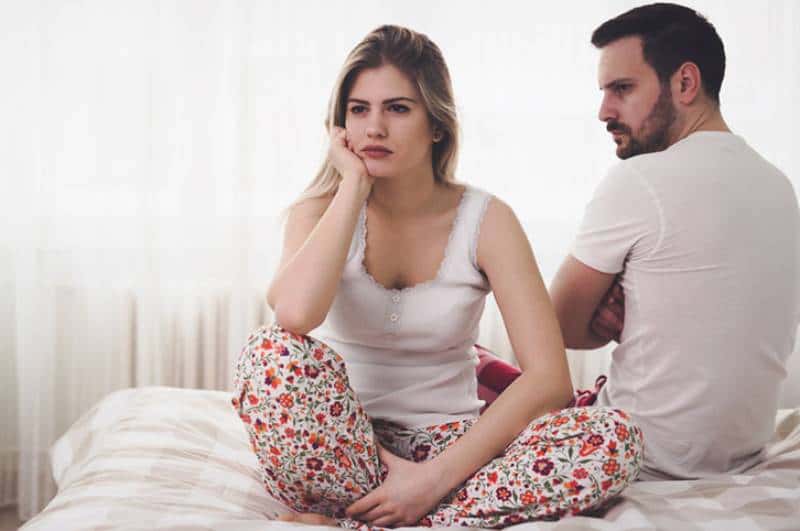 upset couple sitting in bedroom