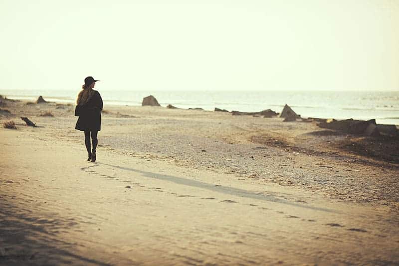 woman walking alone beside sea