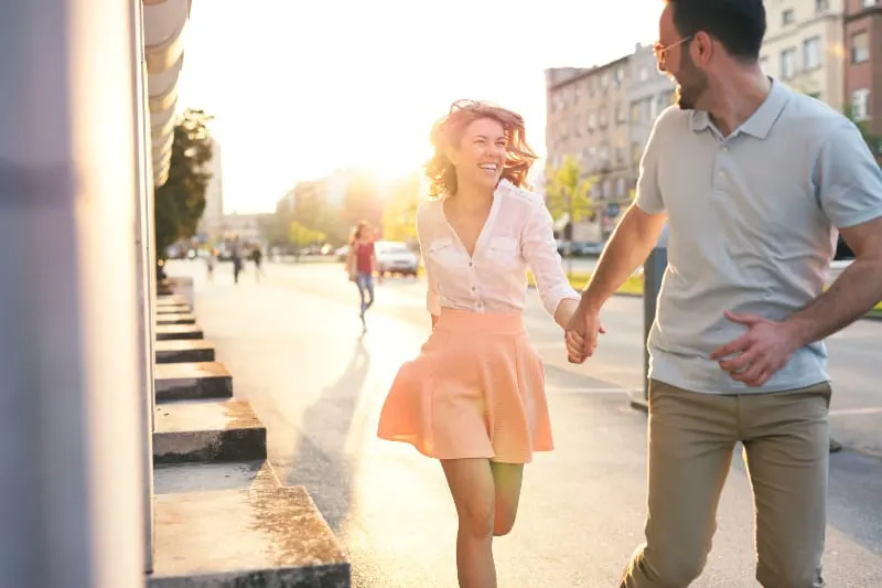 woman wearing pink skirt running with her smiling man on street
