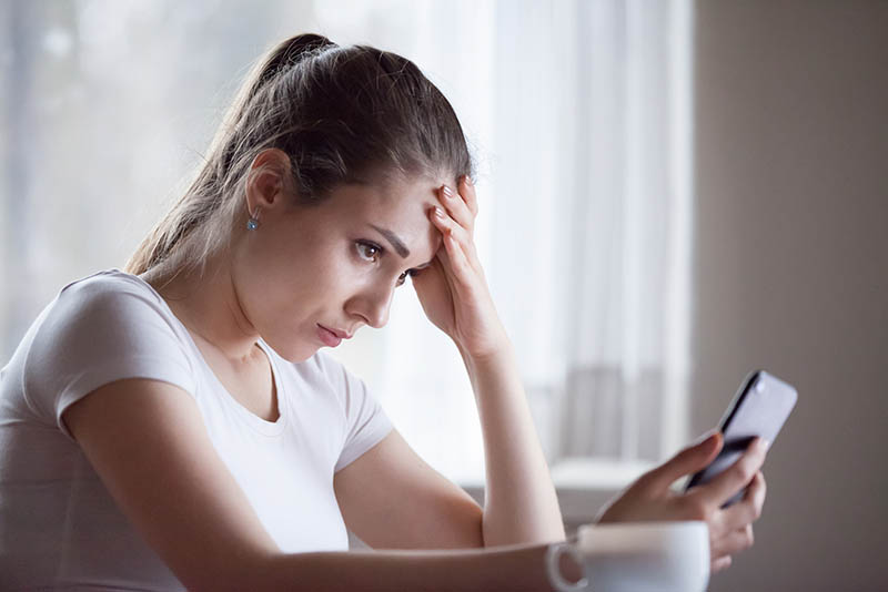 worried young woman looking at mobile phone