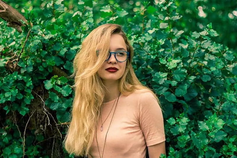 young blonde woman standing beside leafs
