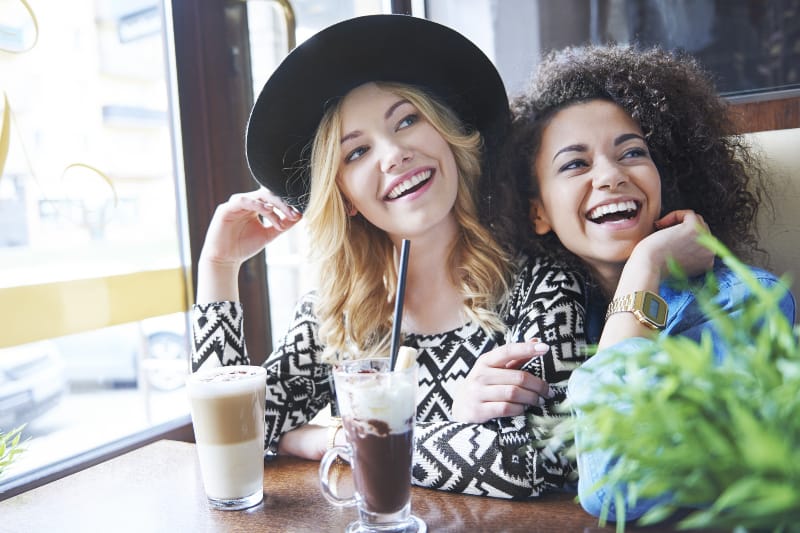 young happy female friends sitting at cafe