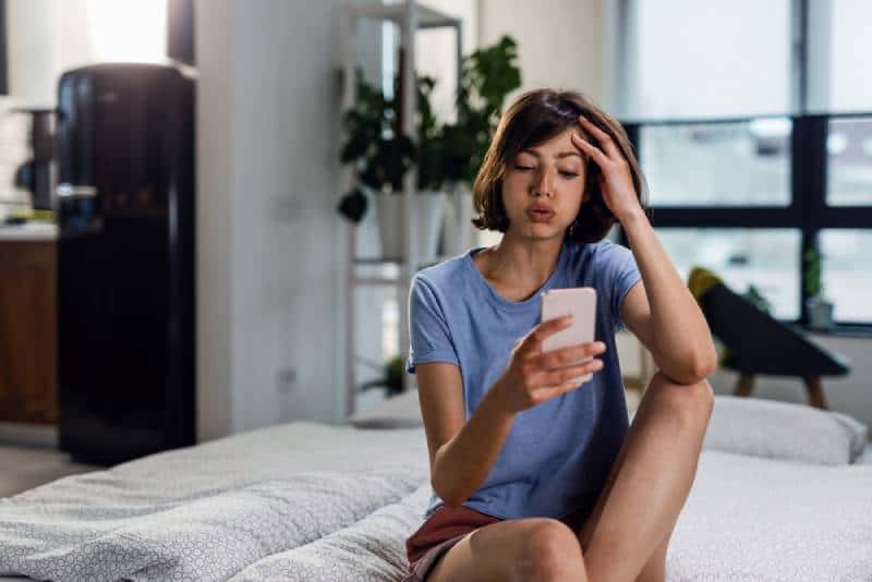 young woman typing on her phone while frowning