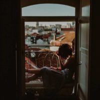 a sad woman sitting at the window