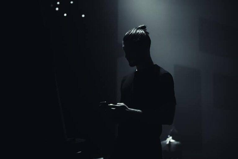silhouette of man typing on his phone in dark