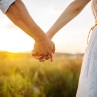 couple holding hands in green field