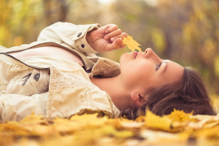 a young girl lying on a dry leaf