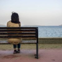 Jovem mulher triste e deprimida sentada sozinha num banco