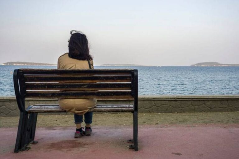 Young sad depressed woman sit alone on bench