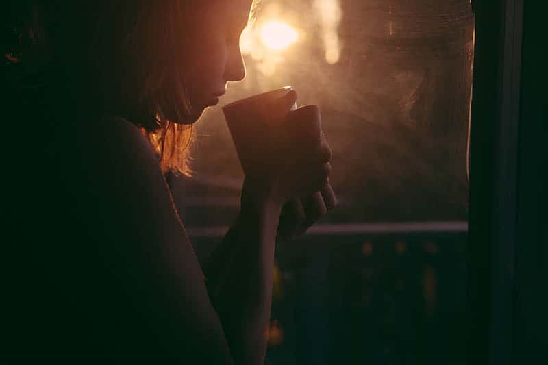 silhouette of woman holding cup of tea