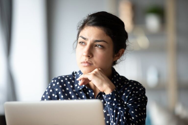pensive woman sitting by the laptop