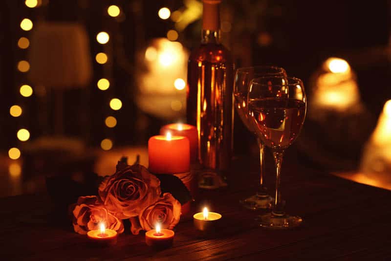 Bella composizione romantica con candele rose e bicchieri di vino