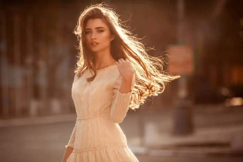 Beautiful young lady with long hair and cute dress on the street