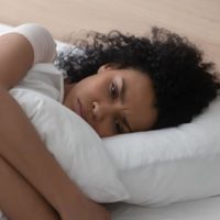 mujer triste tumbada en la cama