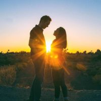silhouette of man and woman standing in front of each other during sunset