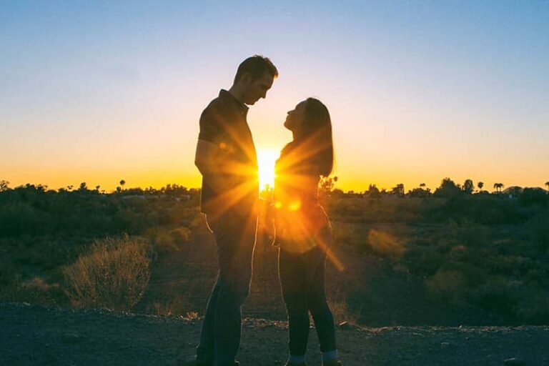 silhouette of man and woman standing in front of each other during sunset