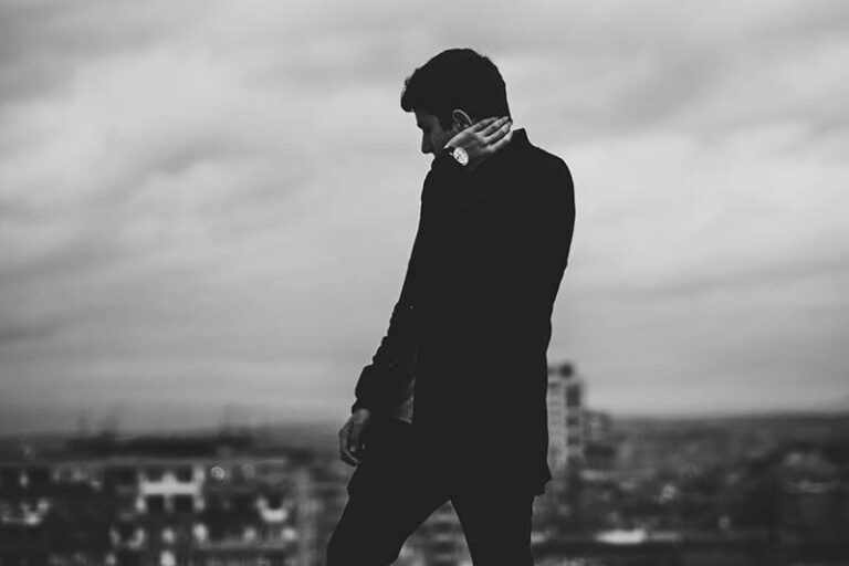 black and white photo of man wearing black jacket standing on rooftop