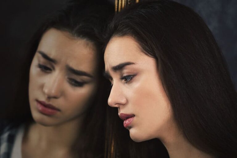 donna triste che si guarda allo specchio