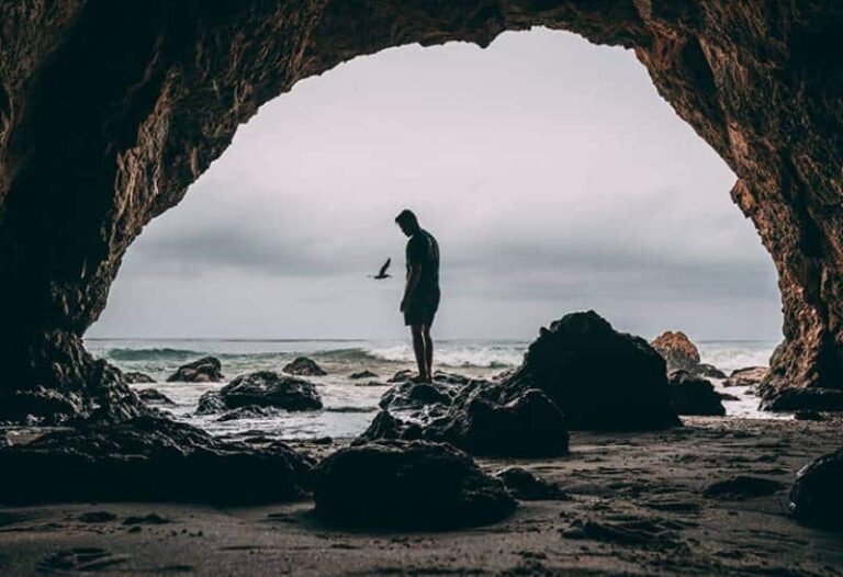 foto di un uomo in piedi su una roccia in riva al mare