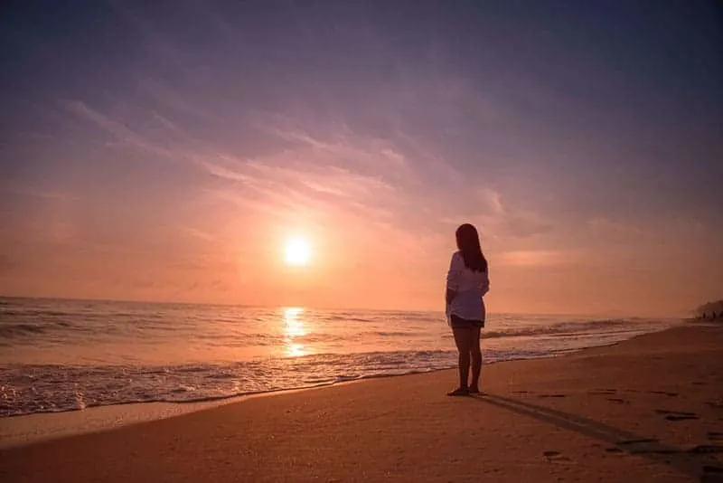 Lonely woman standing on the beach sunset