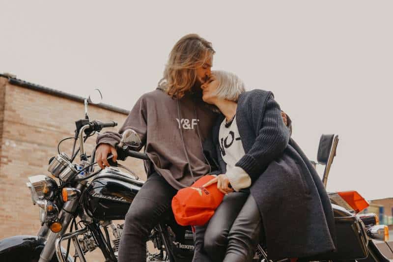 L'uomo bacia la fronte della donna mentre è seduto sulla moto
