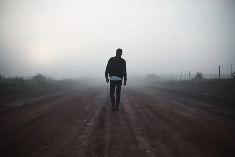 Man walking away on misty road