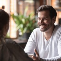 hombre sonriente mirando a una mujer en un café