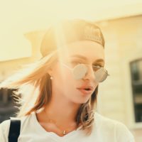 a portrait of a beautiful girl with a cap and sunglasses