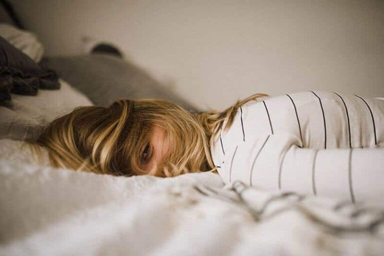 sad woman lying on bed