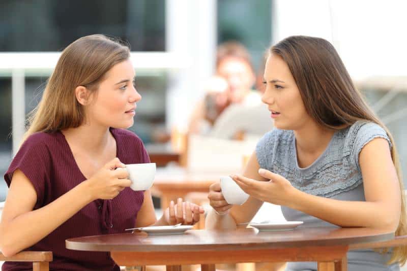 Dos amigos serios conversan sentados en un restaurante