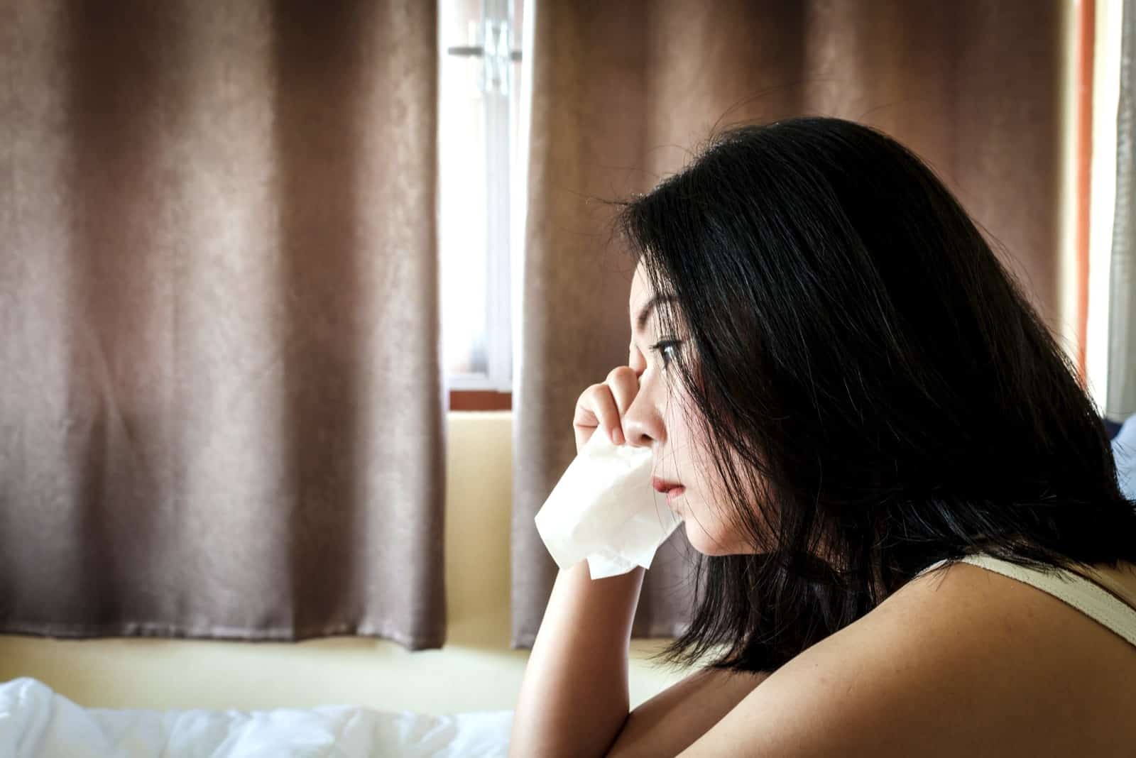 una donna asiatica depressa piange in casa