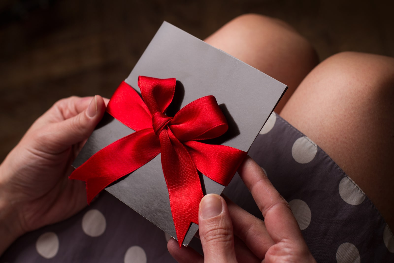 una mujer con un vestido de lunares sostiene una tarjeta regalo en la mano