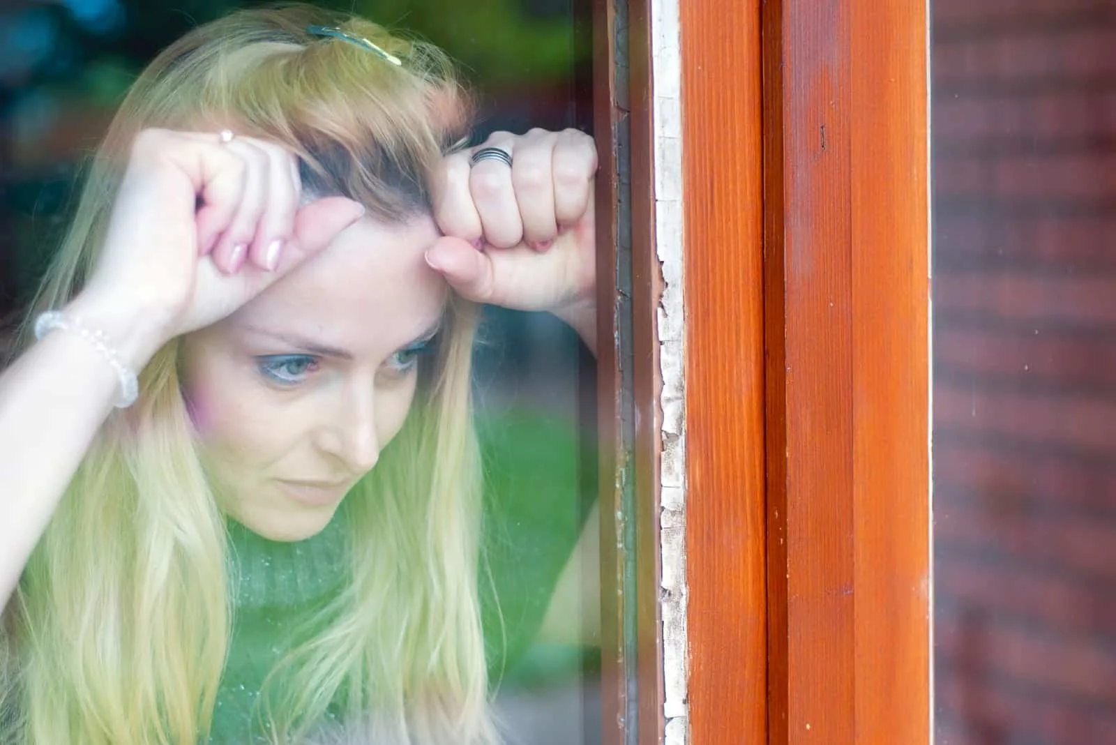anxious sad blonde at the window